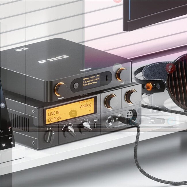 FiiO BR15 R2R מכשיר אודיו שחור  בי.אר. 15 מונח על גבי מגבר שולחני גדול ממנו. שניהם דלוקים עם אור כתום רך ומונחים על מדף לבן צמוד לקיר מחורץ . מצד אחד שלהם יש אוזניות פיו אפ טי 7 ומצד שני מכשיר טלפון נייד על סטנד